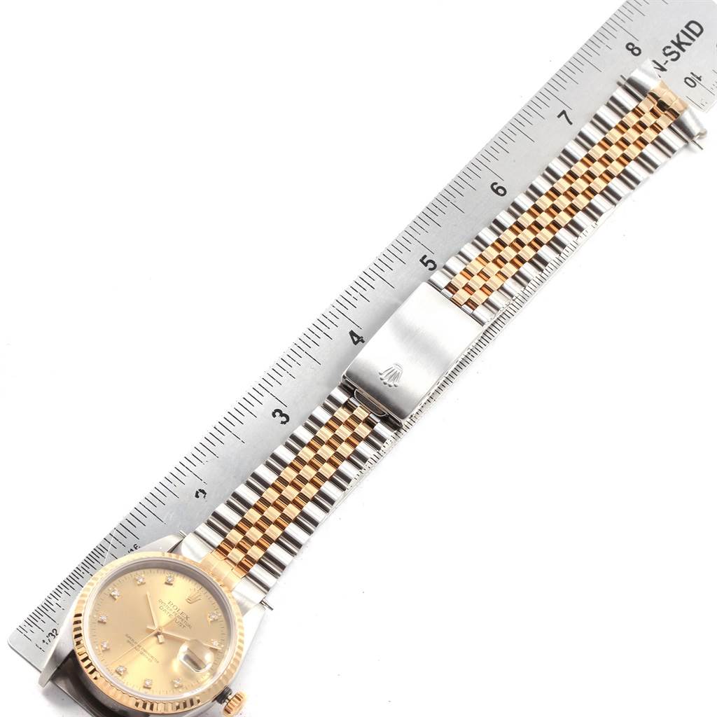 The image shows a Rolex Datejust 16233 Men's Steel and Gold (two tone) Champagne Dial 16233 Men's Steel and Gold (two tone) Champagne Dial watch laid flat alongside a ruler, highlighting its dial, bracelet, and clasp.