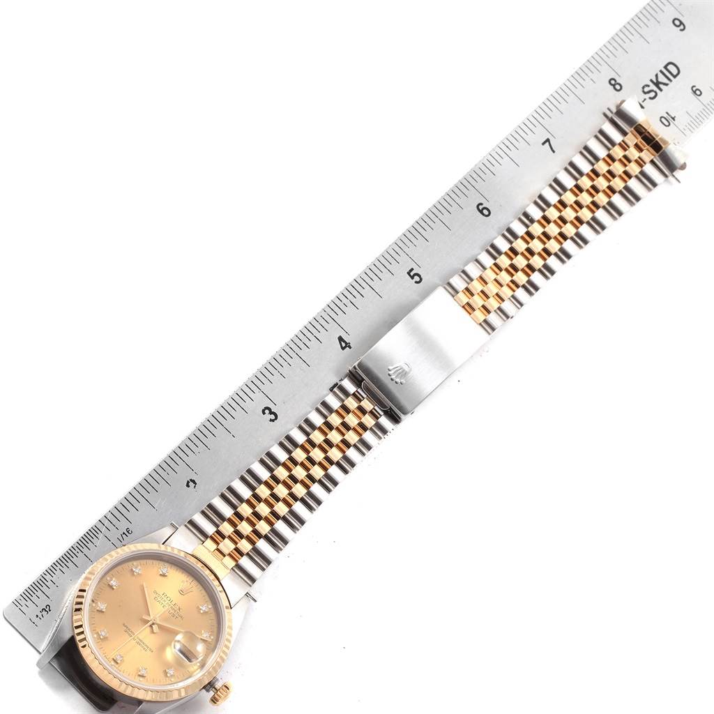 The Rolex Datejust 16233 Men's Steel and Gold (two tone) Champagne Dial 16233 Men's Steel and Gold (two tone) Champagne Dial watch is shown flat with a focus on its face, bracelet, and clasp next to a ruler for measurement.