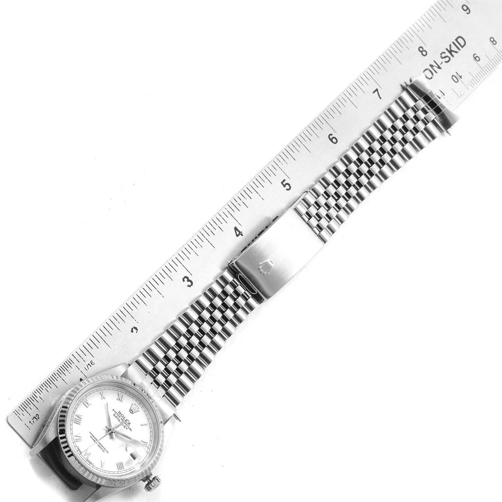 The image shows a Rolex Datejust 16234 Men
s Stainless Steel White Dial 16234 Men
s Stainless Steel White Dial watch laid flat next to a ruler, displaying its face, bracelet, and clasp.