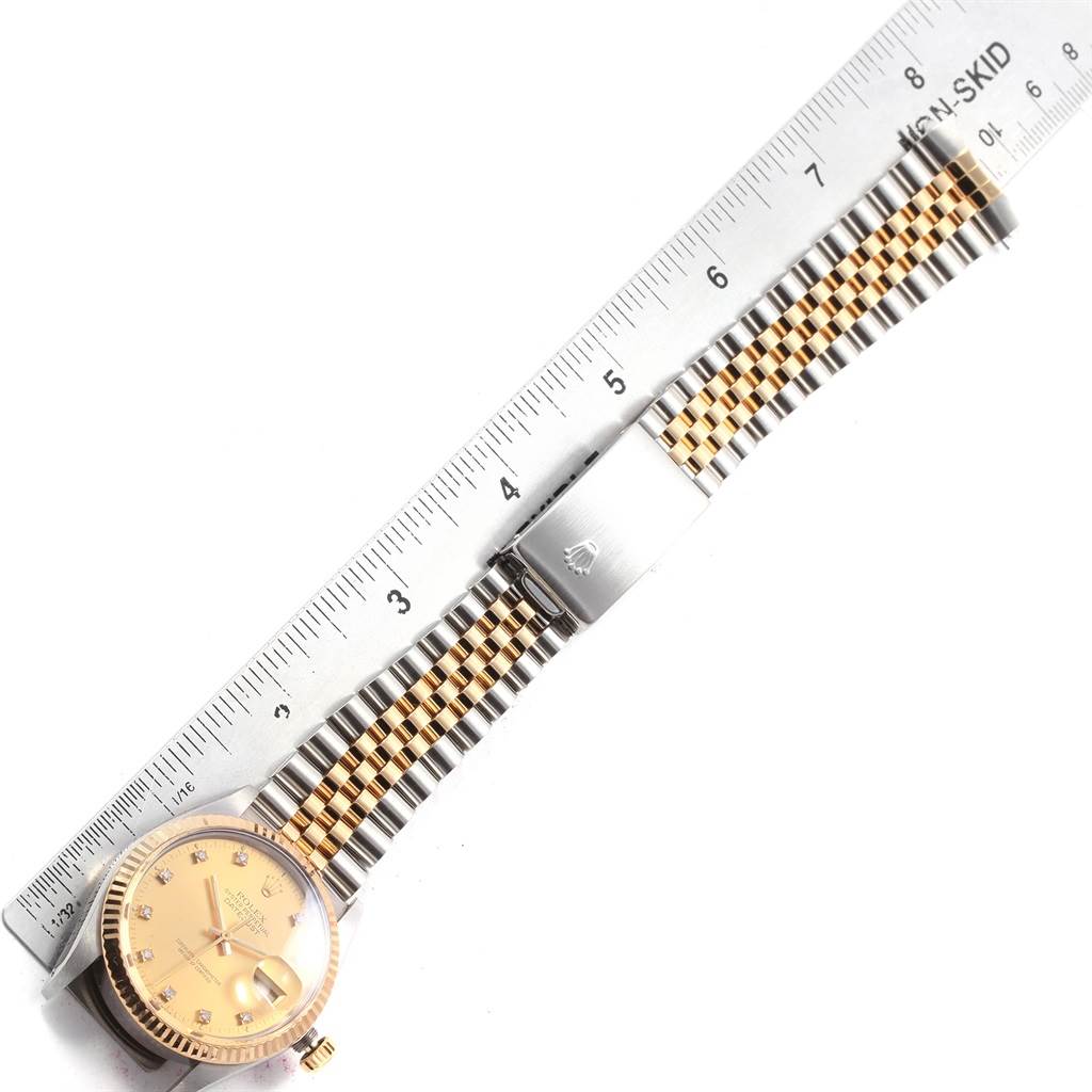 The Rolex Datejust 16013 Men
s Stainless Steel Champagne Dial 16013 Men
s Stainless Steel Champagne Dial watch is shown from a top-down angle, highlighting the face and bracelet alongside a ruler for scale.