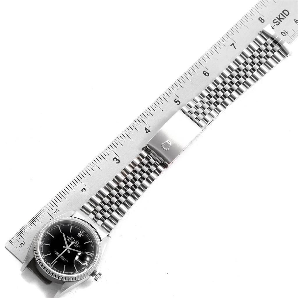 This image shows a Rolex Datejust 16220 Men
s Stainless Steel Black Dial 16220 Men
s Stainless Steel Black Dial watch laid flat, displaying its face, bezel, jubilee bracelet, and clasp, alongside a ruler for scale.