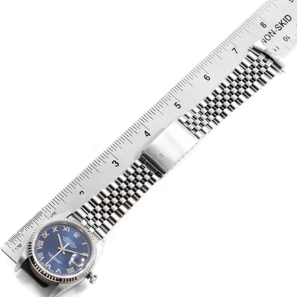 This image shows a top-down view of a Rolex Datejust 16234 Men's Stainless Steel Blue Dial 16234 Men's Stainless Steel Blue Dial watch with a blue dial and a stainless steel jubilee bracelet next to a ruler.