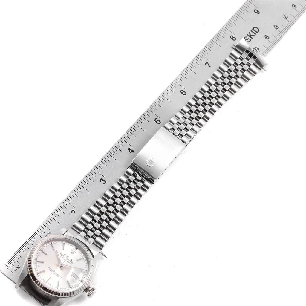 The Rolex Datejust 16234 Men's Stainless Steel Silver Dial 16234 Men's Stainless Steel Silver Dial watch is shown from a top view, displaying the face, bezel, and complete band alongside a ruler.