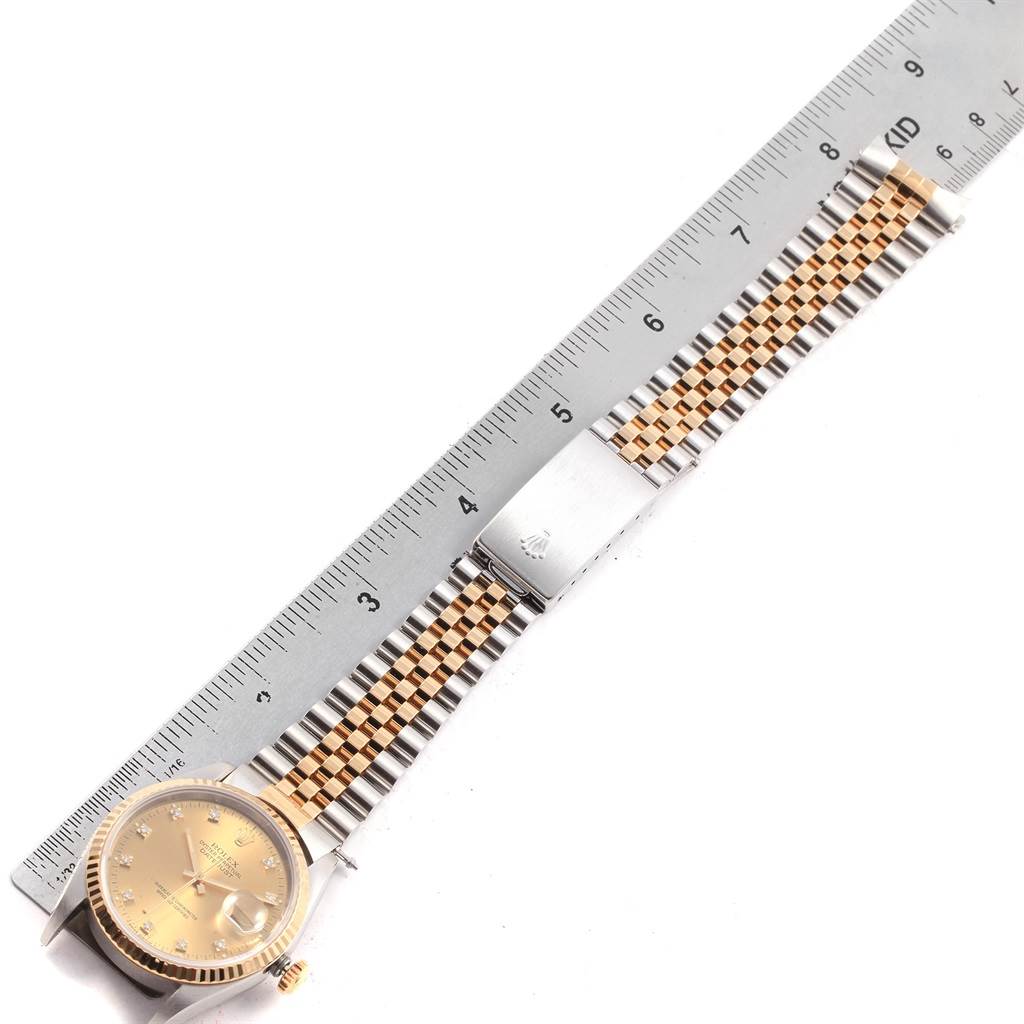 The image displays a Rolex Datejust 16233 Men's Steel and Gold (two tone) Champagne Dial 16233 Men's Steel and Gold (two tone) Champagne Dial watch laid flat next to a ruler, showcasing its face, band, and clasp.