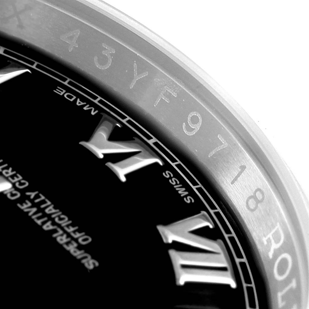 The image shows a close-up of a Rolex Datejust 116200 Men
s Stainless Steel Black Dial 116200 Men
s Stainless Steel Black Dial watch bezel, highlighting the Roman numerals and part of the serial number engraving.