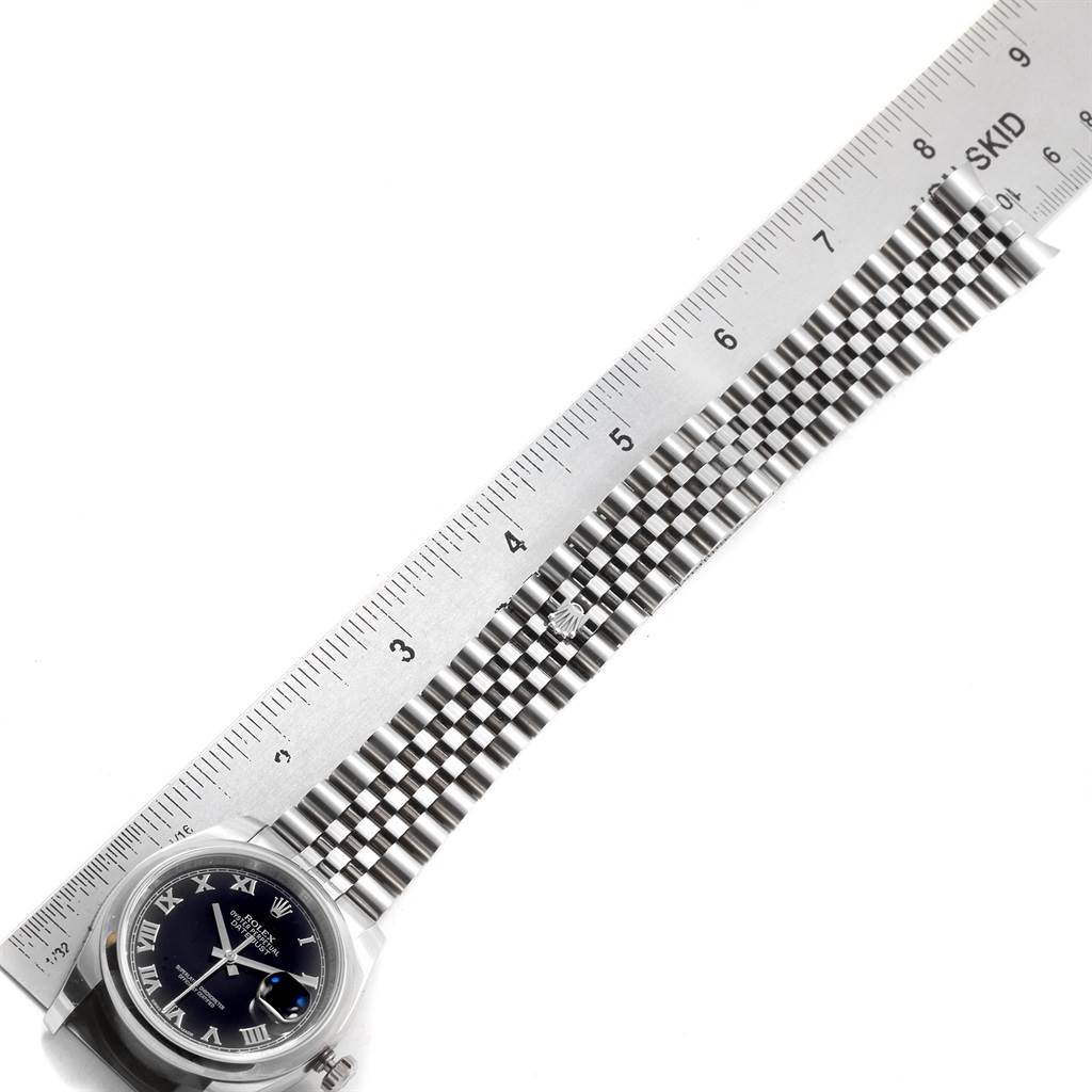 This image shows a Rolex Datejust 116200 Men
s Stainless Steel Black Dial 116200 Men
s Stainless Steel Black Dial watch with its face and full bracelet displayed alongside a measuring ruler.