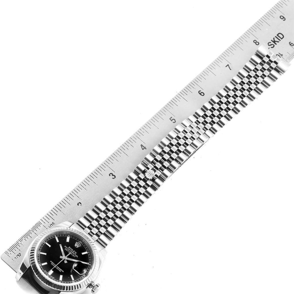 The image shows a top-down view of a Rolex Datejust 116234 Men
s Stainless Steel Black Dial 116234 Men
s Stainless Steel Black Dial watch, including its face and metal bracelet, measured alongside a ruler.