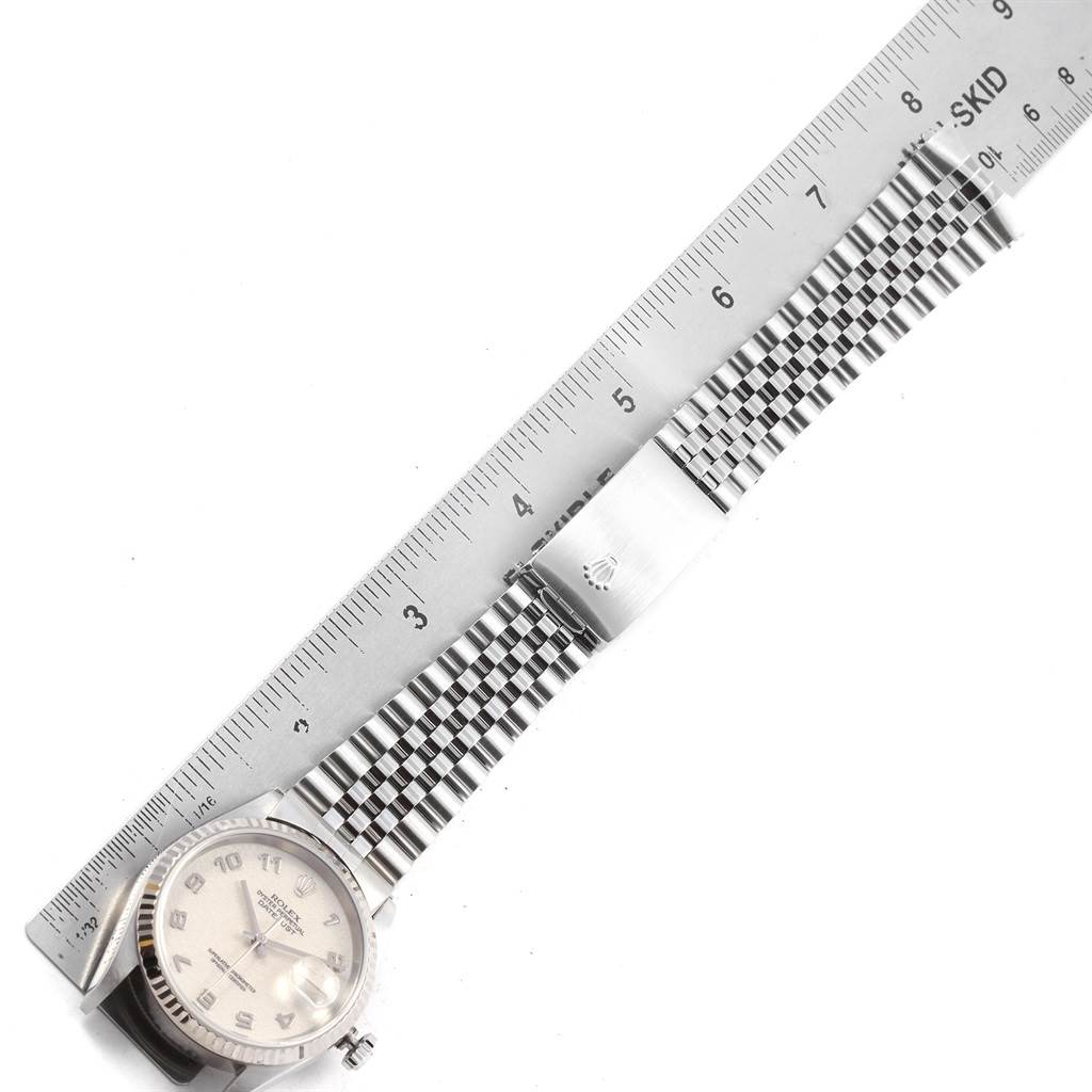 The image shows a top-down view of a Rolex Datejust 16234 Men's Stainless Steel Silver Dial 16234 Men's Stainless Steel Silver Dial model watch, displaying the face, bracelet, and clasp next to a ruler for scale.