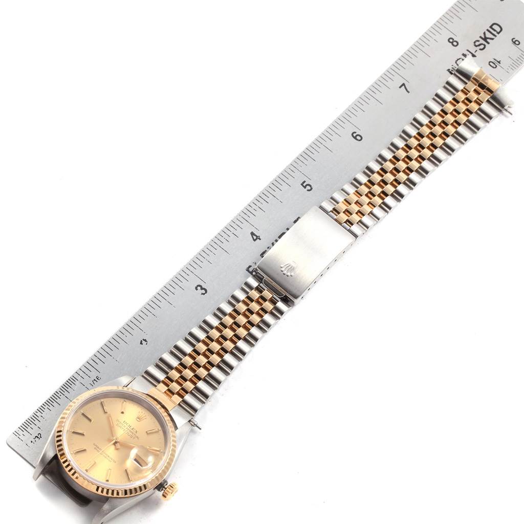 The Rolex Datejust 16233 Men's Steel and Gold (two tone) Champagne Dial 16233 Men's Steel and Gold (two tone) Champagne Dial watch is shown laid flat with a ruler for scale, displaying its full face and metal strap.
