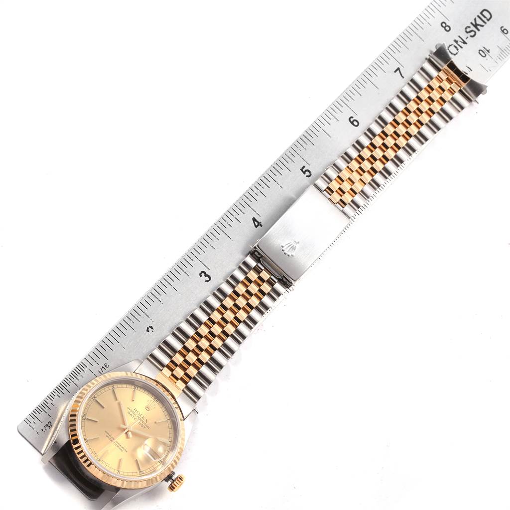 The Rolex Datejust 16233 Men
s Steel and Gold (two tone) Champagne Dial 16233 Men
s Steel and Gold (two tone) Champagne Dial watch is shown flat with a ruler, displaying the bezel, dial, crown, and part of the bracelet.