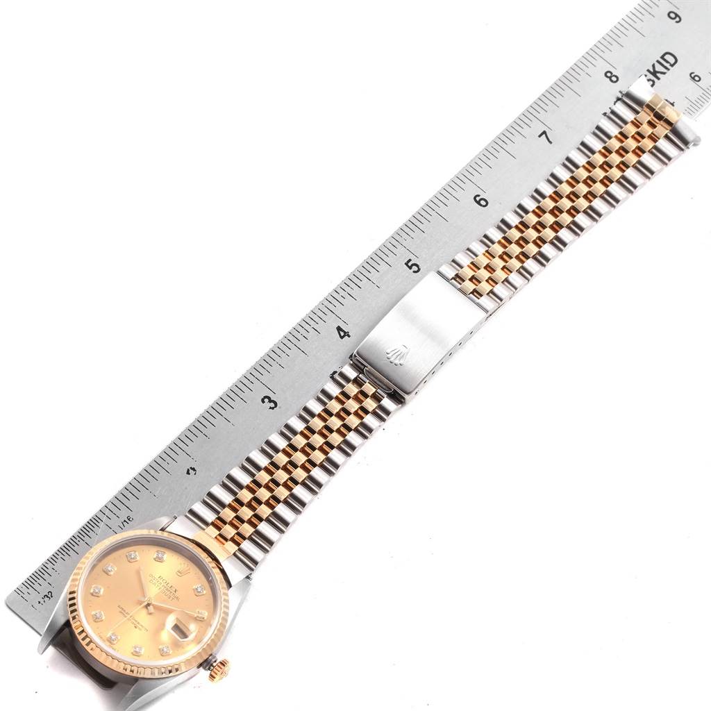 The Rolex Datejust 16233 Men's Steel and Gold (two tone) Champagne Dial 16233 Men's Steel and Gold (two tone) Champagne Dial watch is shown from a top-down angle, highlighting its dial, bezel, and jubilee bracelet with a ruler for scale.