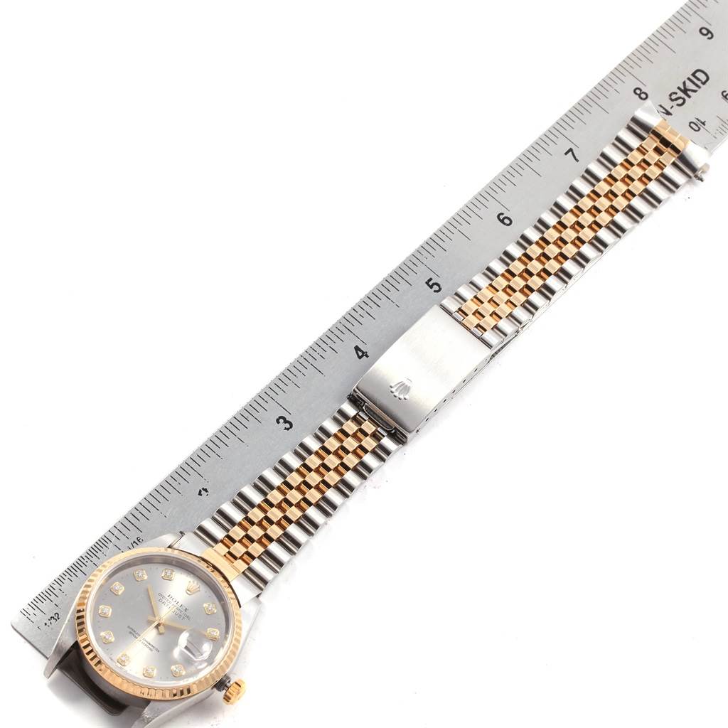 The image shows a Rolex Datejust 16233 Men's Steel and Gold (two tone) Silver Dial 16233 Men's Steel and Gold (two tone) Silver Dial watch placed horizontally with its full bracelet and clasp next to a ruler.