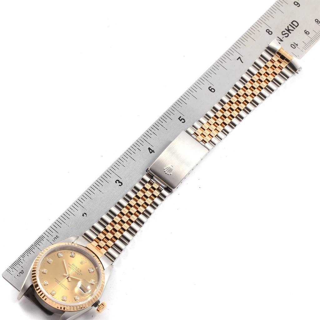 This image shows a Rolex Datejust 16233 Men's Steel and Gold (two tone) Champagne Dial 16233 Men's Steel and Gold (two tone) Champagne Dial watch laid flat, displaying its face, fluted bezel, and Jubilee bracelet beside a ruler.