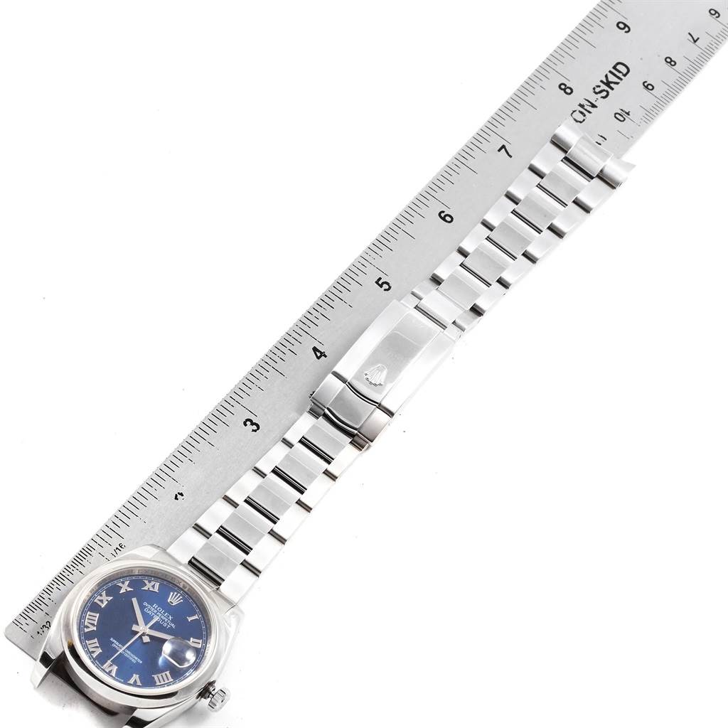 The image shows a top-down angle of a Datejust watch by Rolex, including the face, band, and clasp next to a ruler.