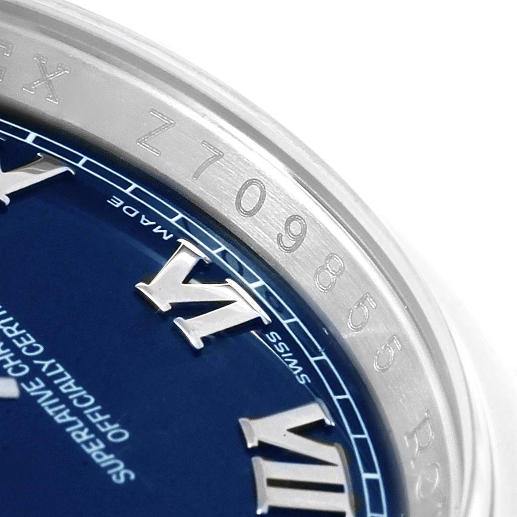 The image shows a close-up of the Rolex Datejust 116200 Men's Stainless Steel Blue Dial 116200 Men's Stainless Steel Blue Dial watch face, highlighting the Roman numerals and serial number engraving on the bezel.