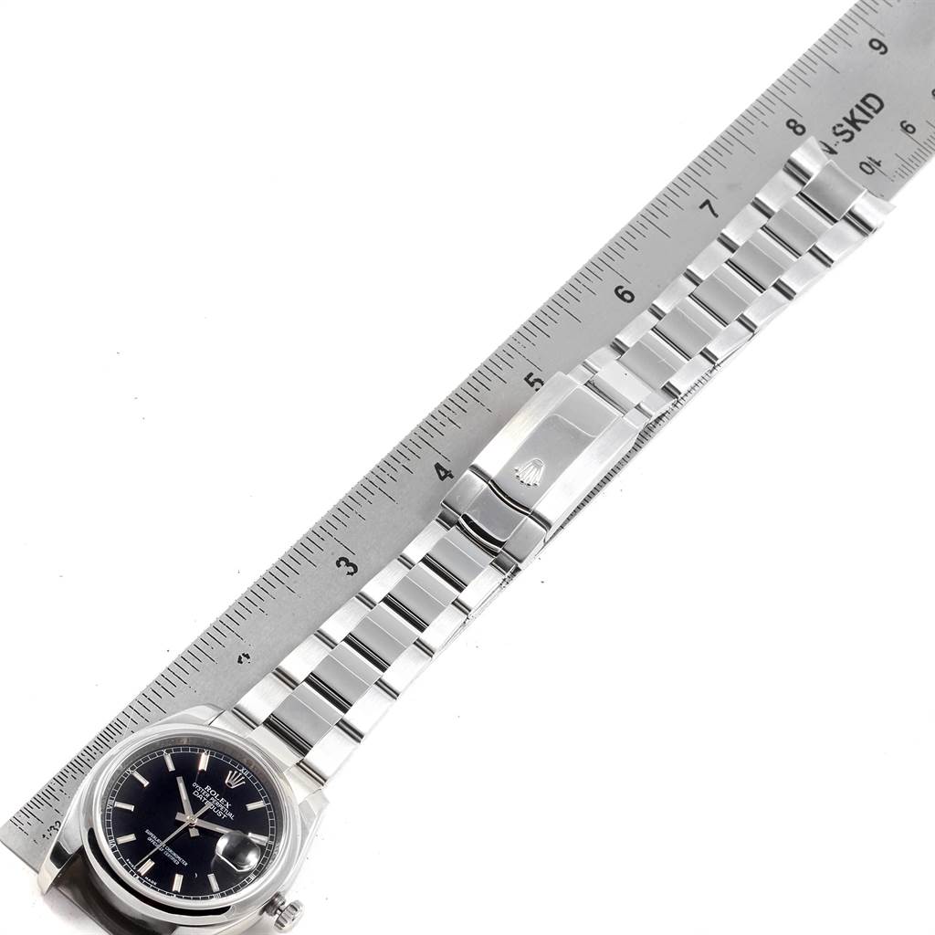 The image shows a Rolex Datejust 116200 Men's Stainless Steel Black Dial 116200 Men's Stainless Steel Black Dial watch laid flat next to a ruler, displaying its dial, bracelet, and clasp.