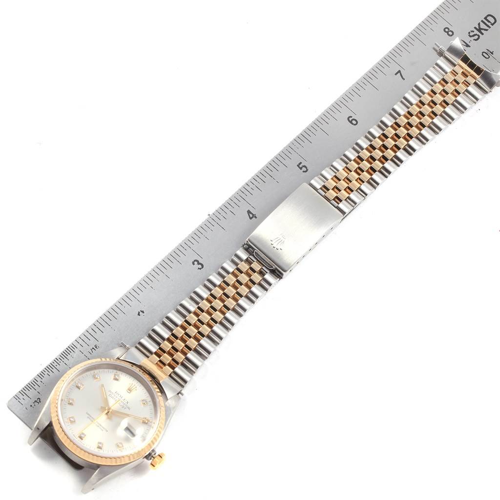 The Rolex Datejust 16233 Men's Steel and Gold (two tone) Silver Dial 16233 Men's Steel and Gold (two tone) Silver Dial watch is shown from a top-down angle, displaying its bracelet, clasp, and part of its dial.