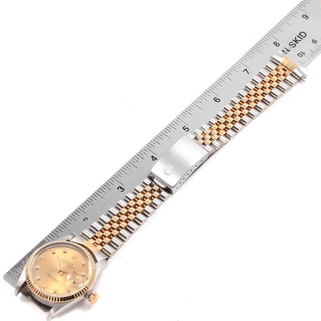 This image shows the Rolex Datejust 16013 Men
s Stainless Steel Champagne Dial 16013 Men
s Stainless Steel Champagne Dial watch laid flat, highlighting the face, jubilee bracelet, and clasp next to a ruler.