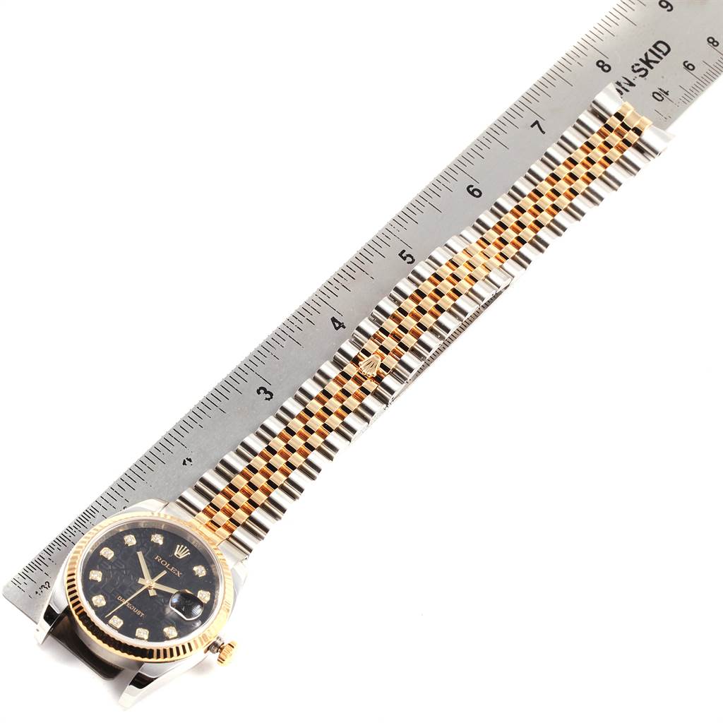 The image shows a Rolex Datejust 116233 Men's Stainless Steel Black Dial 116233 Men's Stainless Steel Black Dial watch with its face, bracelet, and part of the bezel from a top view, alongside a ruler.