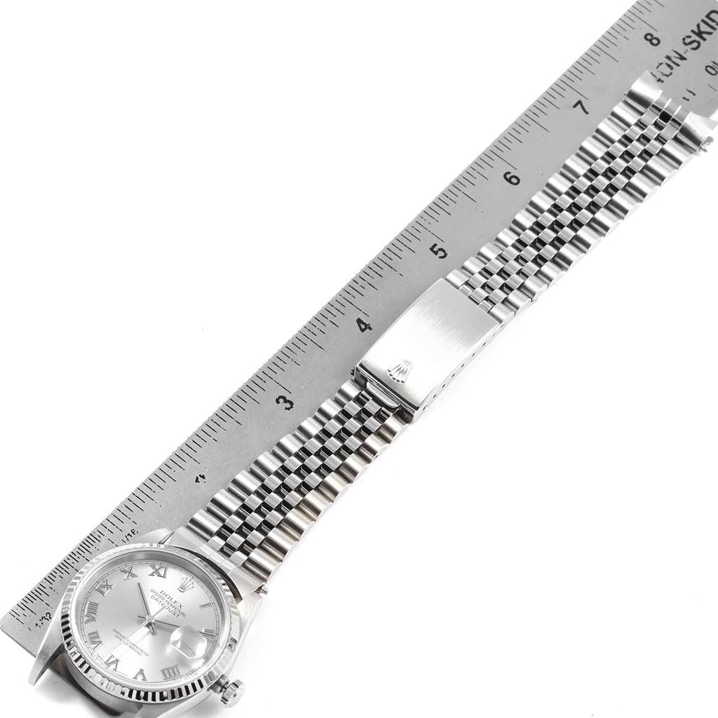 This image shows a Rolex Datejust 16234 Men
s Stainless Steel Silver Dial 16234 Men
s Stainless Steel Silver Dial watch laid flat with a ruler, highlighting its face, bracelet, and clasp.