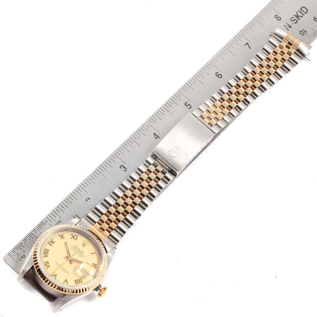 The image shows a Rolex Datejust 16233 Men
s Steel and Gold (two tone) Champagne Dial 16233 Men
s Steel and Gold (two tone) Champagne Dial watch with a two-tone bracelet, flat and fully extended next to a ruler.