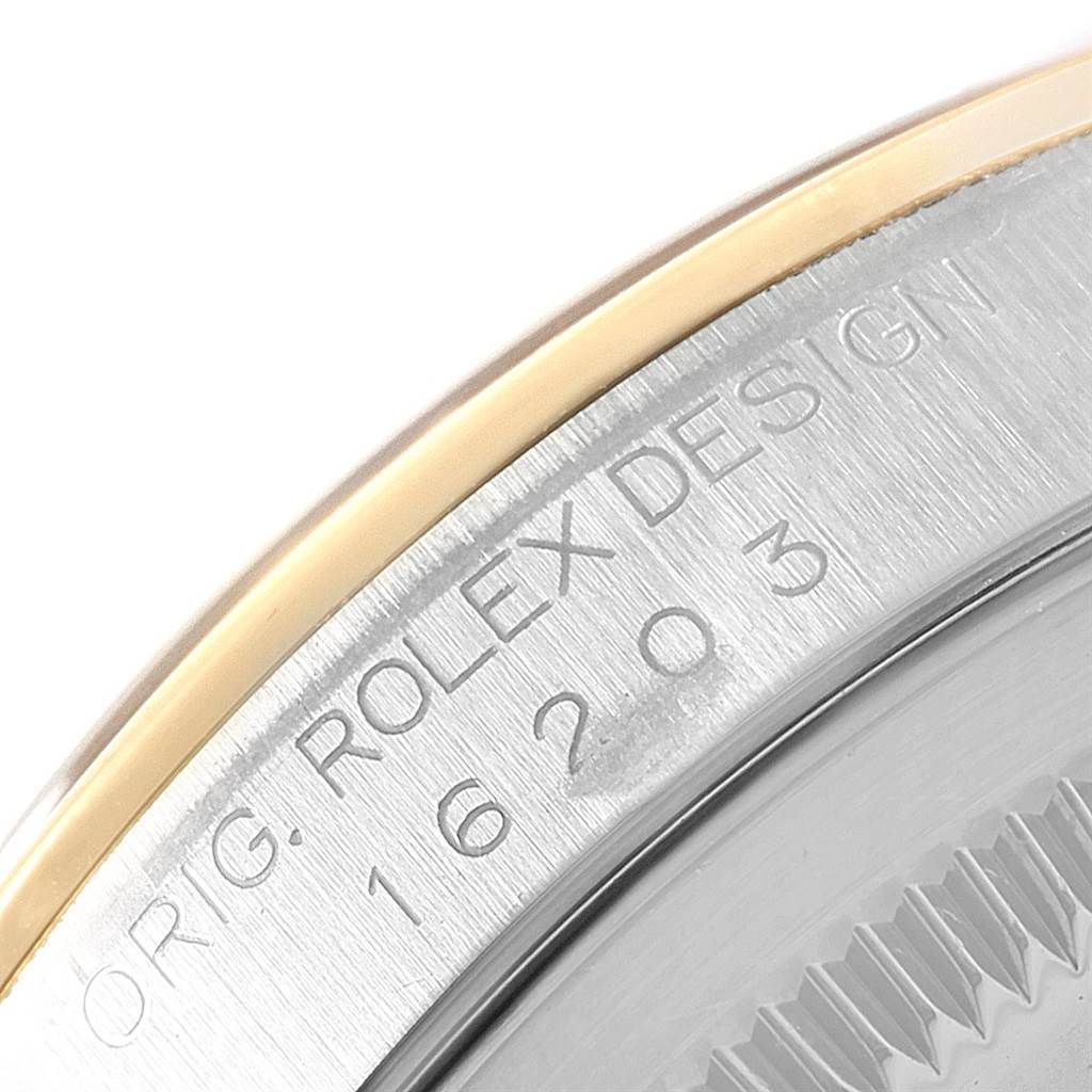 This close-up image shows the engraved model number and part of the bezel of a Rolex Datejust 16203 Men's Steel and Gold (two tone) Black Dial 16203 Men's Steel and Gold (two tone) Black Dial watch.