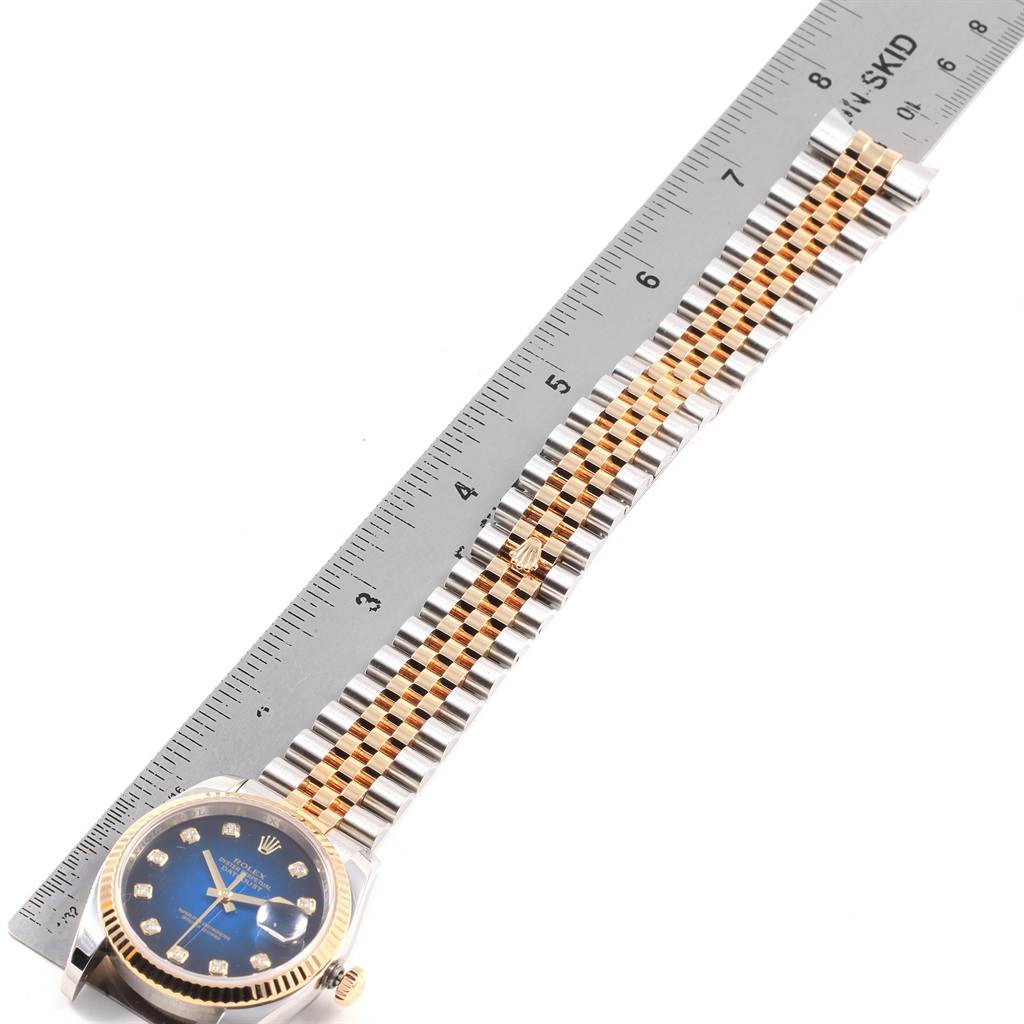 This image shows a top-down view of a Rolex Datejust 116233 Men's Stainless Steel Blue Dial 116233 Men's Stainless Steel Blue Dial watch, including the face, bezel, and bracelet alongside a ruler.