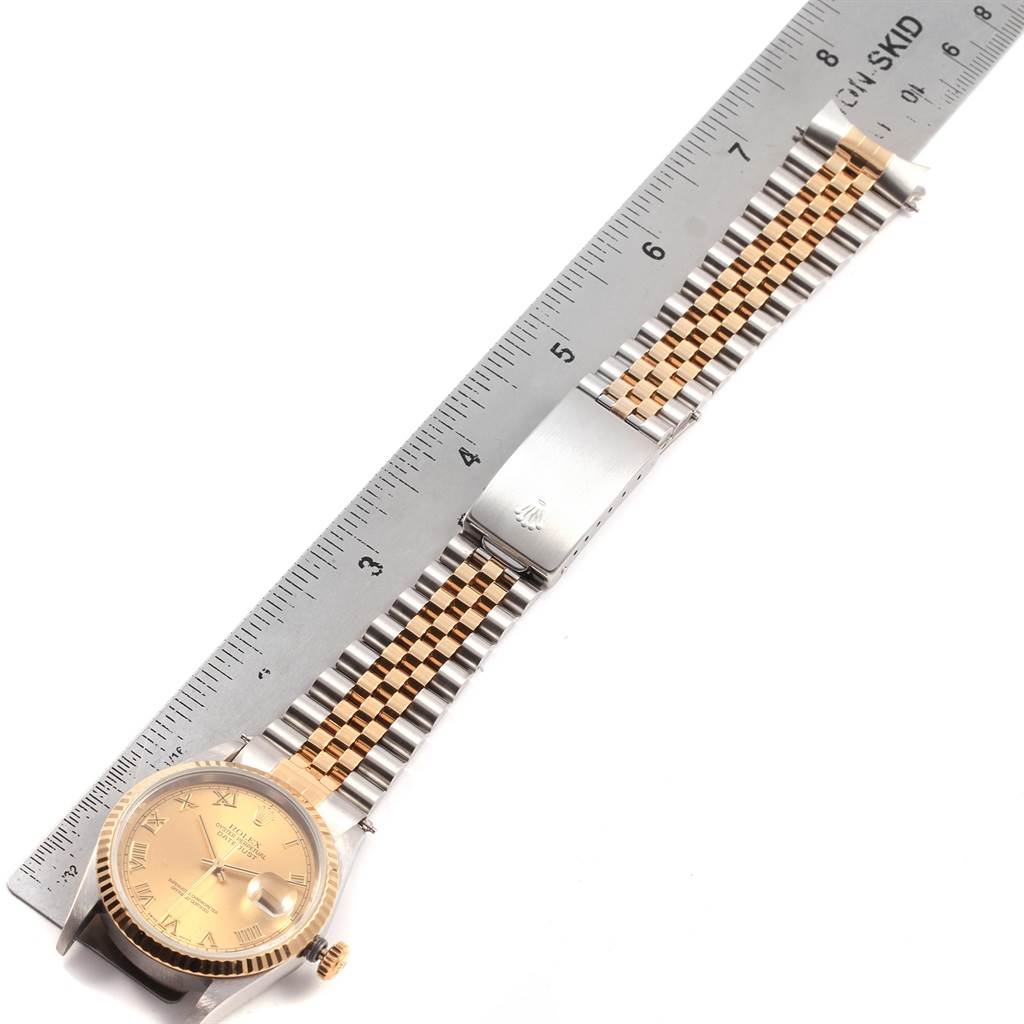 The Rolex Datejust 16233 Men's Steel and Gold (two tone) Champagne Dial 16233 Men's Steel and Gold (two tone) Champagne Dial watch is shown laying flat with its full face, bezel, bracelet, and clasp visible alongside a ruler for scale.