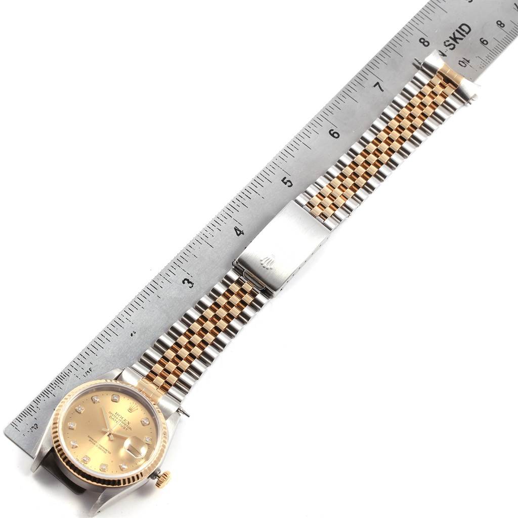 The Rolex Datejust 16233 Men
s Steel and Gold (two tone) Champagne Dial 16233 Men
s Steel and Gold (two tone) Champagne Dial watch is shown from a top-down angle, highlighting the face, bezel, bracelet, and a ruler for scale.