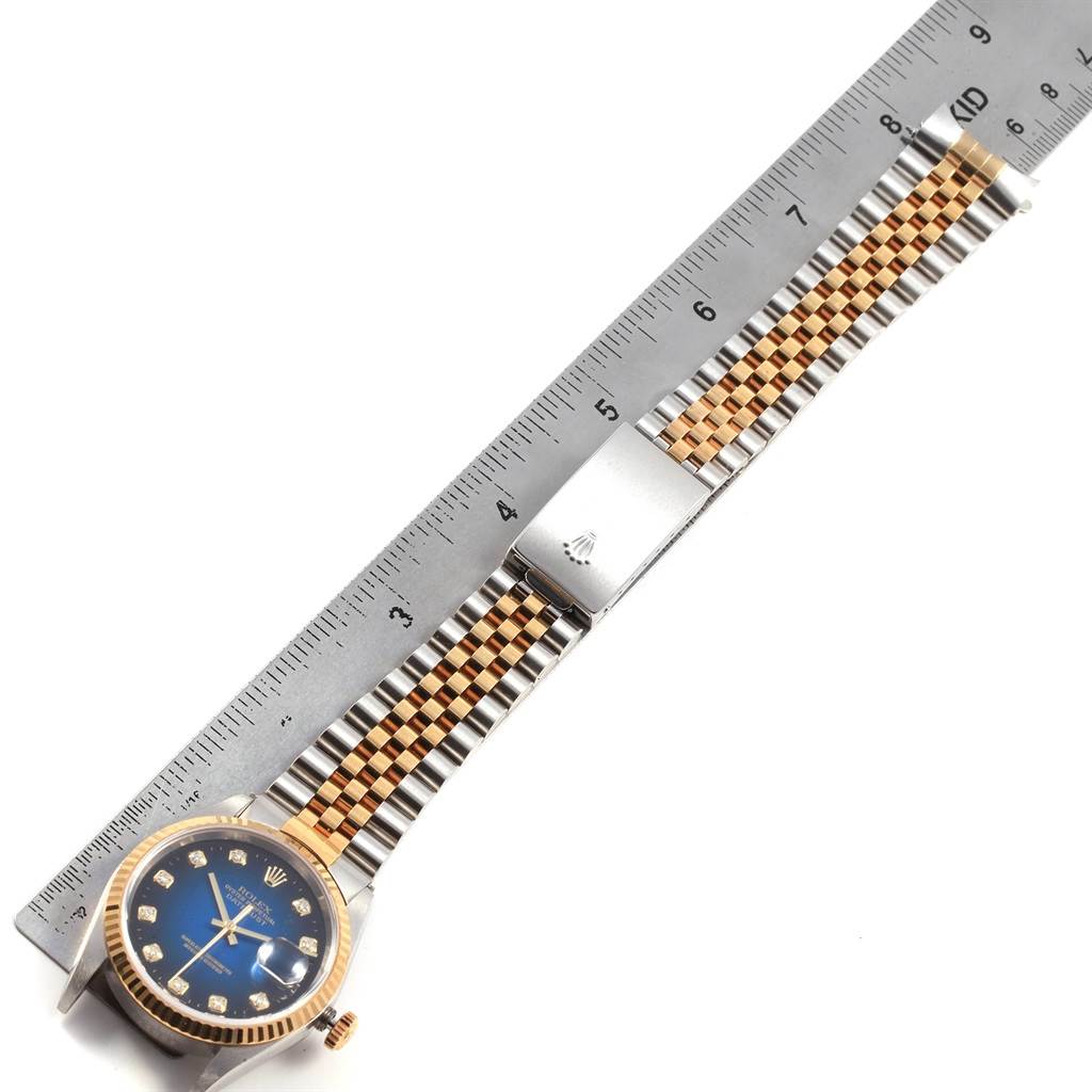 The image shows a Rolex Datejust 16233 Men
s Steel and Gold (two tone) Blue Dial 16233 Men
s Steel and Gold (two tone) Blue Dial watch laid flat, measured with a metal ruler, highlighting the face, crown, and bracelet.