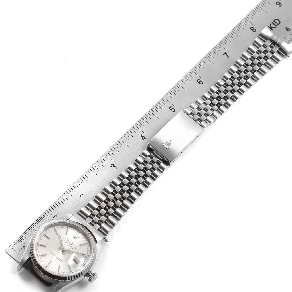The image shows a top-down view of a Rolex Datejust 16234 Men's Stainless Steel Silver Dial 16234 Men's Stainless Steel Silver Dial watch, highlighting the face, bezel, and bracelet next to a ruler for scale.