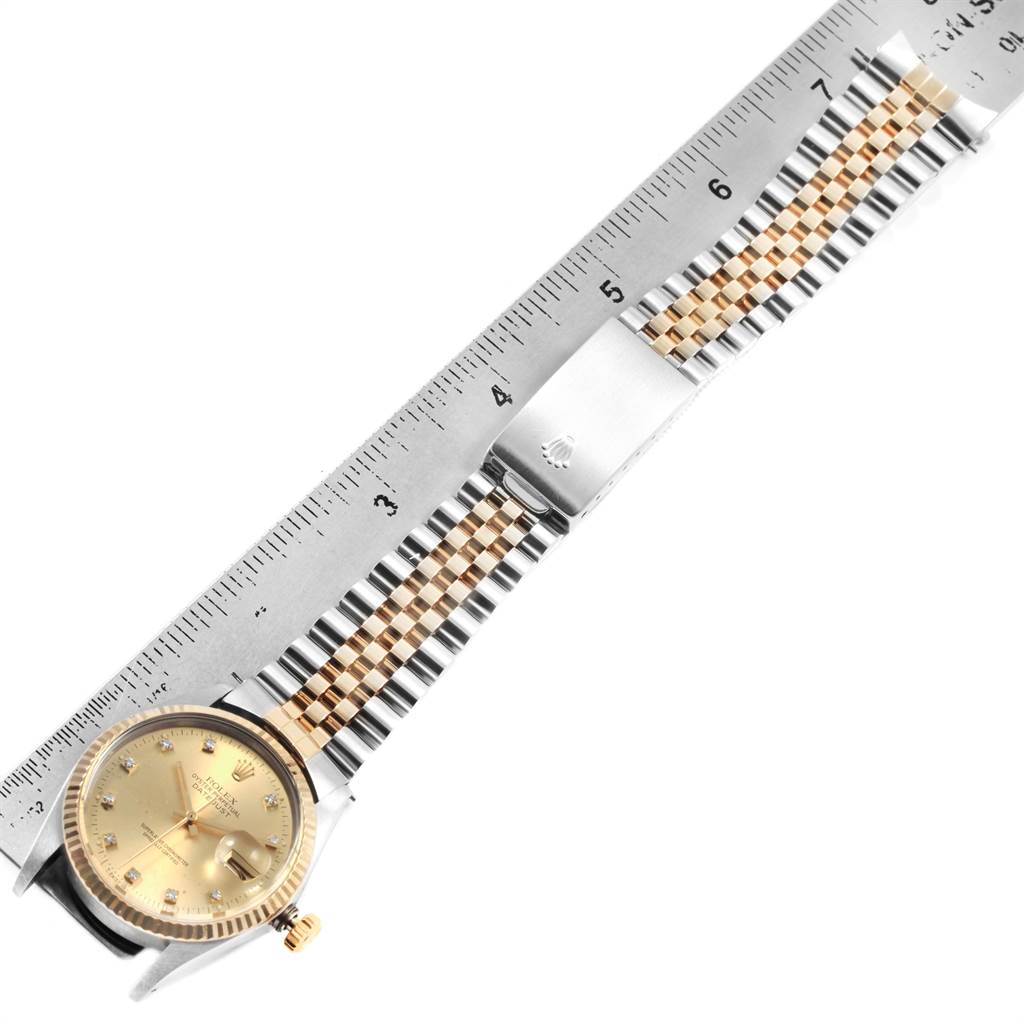 The Rolex Datejust 16013 Men's Stainless Steel Champagne Dial 16013 Men's Stainless Steel Champagne Dial watch is shown from a top-down angle, highlighting its dial, bezel, and Jubilee bracelet with an attached ruler for scale.