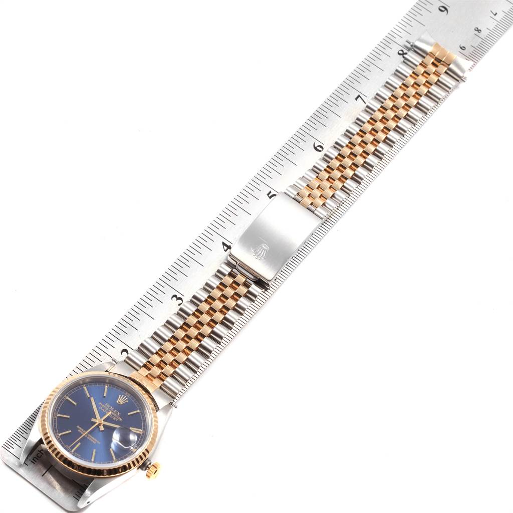 The image shows a top view of a Rolex Datejust 16233 Men's Steel and Gold (two tone) Blue Dial 16233 Men's Steel and Gold (two tone) Blue Dial model watch, highlighting the face, bezel, crown, and bracelet alongside a ruler.