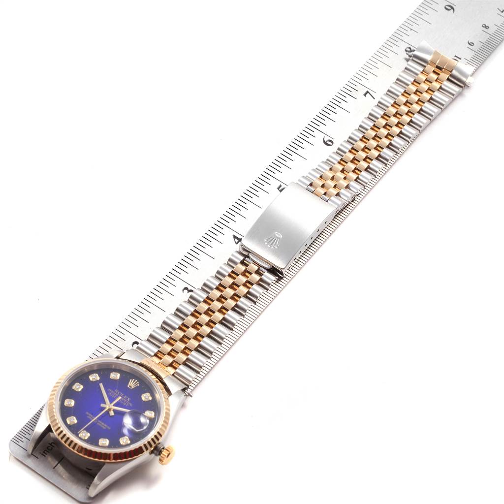The image shows a Rolex Datejust 16233 Men's Steel and Gold (two tone) Blue Dial 16233 Men's Steel and Gold (two tone) Blue Dial watch, featuring the face, crown, and bracelet aligned with a ruler.