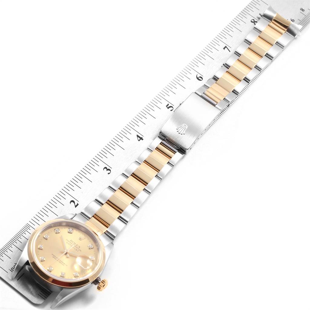 The image shows the Rolex Datejust 16203 Men's Steel and Gold (two tone) Champagne Dial 16203 Men's Steel and Gold (two tone) Champagne Dial watch laid flat with a ruler for scale, highlighting the gold and silver bracelet.