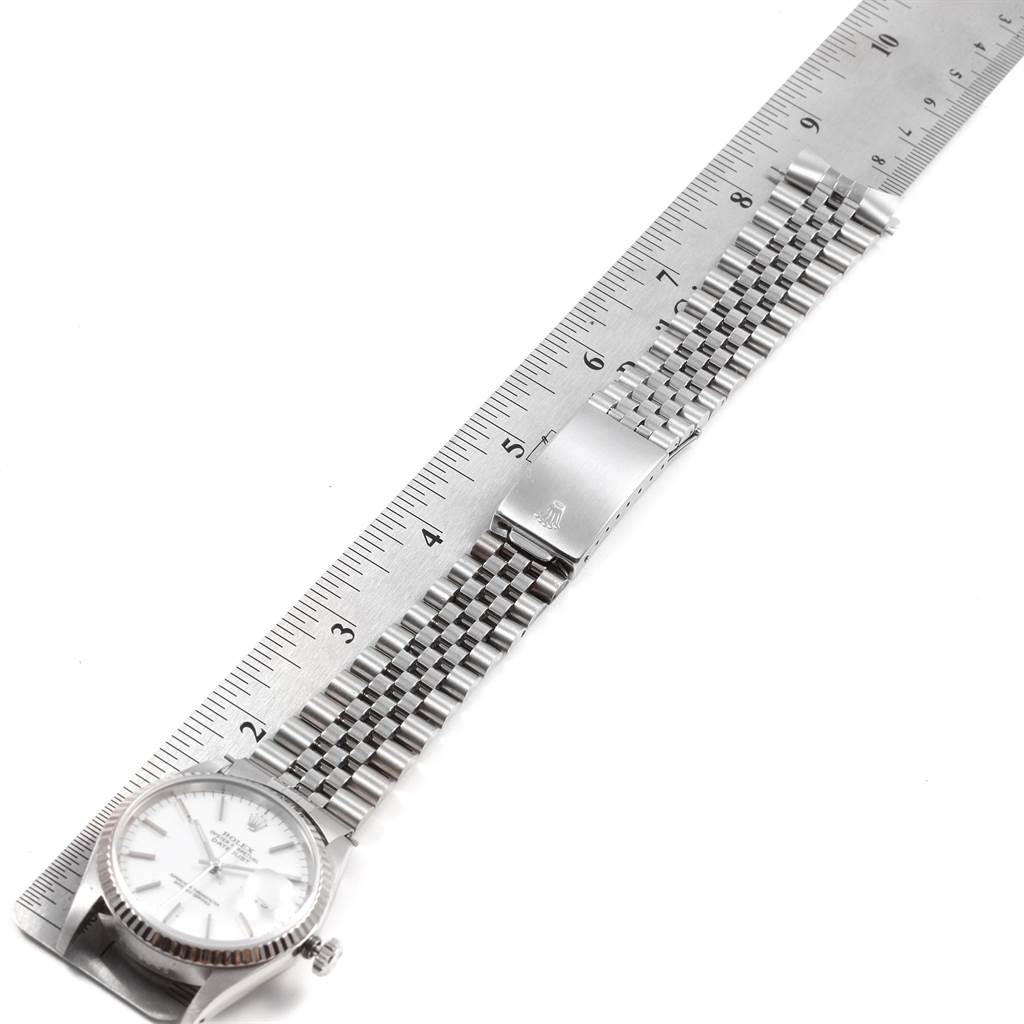 The Rolex Datejust 16234 Men
s Stainless Steel White Dial 16234 Men
s Stainless Steel White Dial watch is shown flat with its dial, bracelet, and clasp visible alongside a measuring ruler.