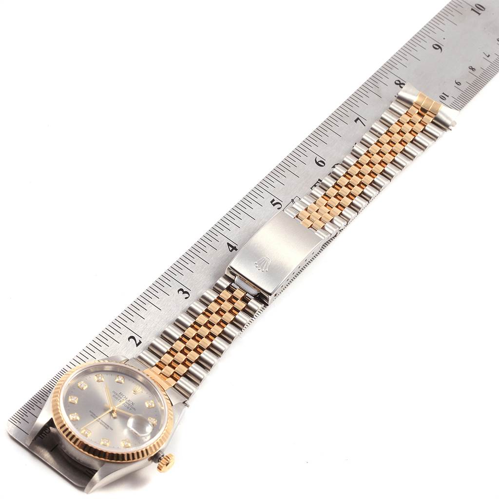 The image shows a Rolex Datejust 16233 Men's Steel and Gold (two tone) Silver Dial 16233 Men's Steel and Gold (two tone) Silver Dial watch laid flat next to a ruler, highlighting its bracelet, clasp, and case.