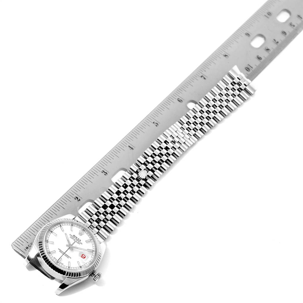 The image shows a Rolex Datejust 116234 Men's Stainless Steel White Dial 116234 Men's Stainless Steel White Dial watch laid next to a ruler, displaying its face, case, and bracelet.