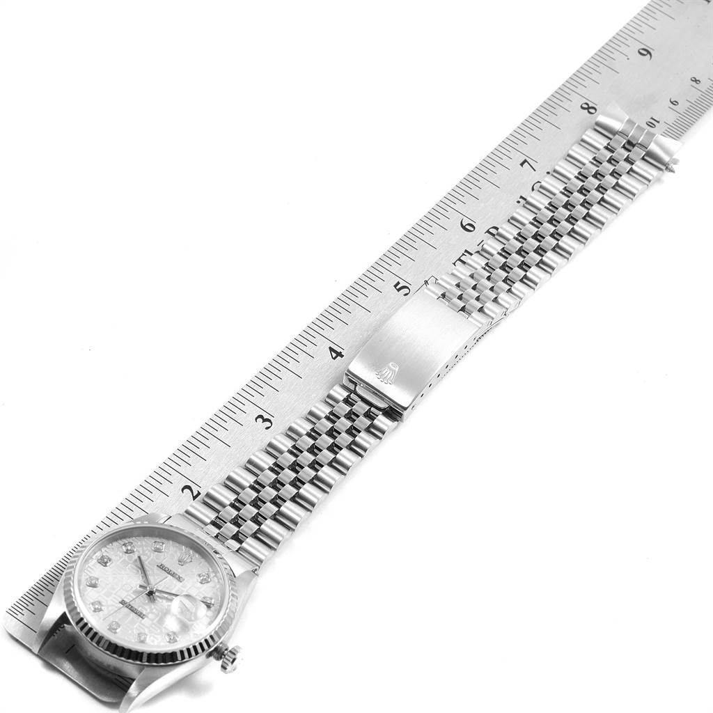 The image shows a Rolex Datejust 16234 Men
s Stainless Steel Silver Dial 16234 Men
s Stainless Steel Silver Dial watch from an elevated angle, detailing the face and metal bracelet next to a ruler.