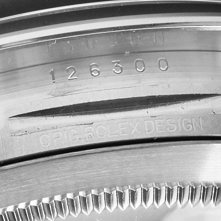 Close-up view of the serial number and "ORIG.ROLEX DESIGN" engraved on the bezel of a Rolex Datejust 126300 Men
s Stainless Steel Black Dial 126300 Men
s Stainless Steel Black Dial watch.