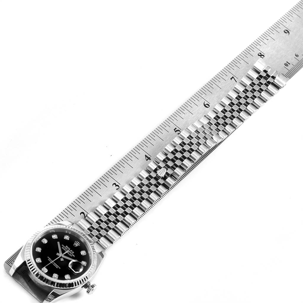 This image shows a side angle of the Rolex Datejust 116234 Men's Stainless Steel Black Dial 116234 Men's Stainless Steel Black Dial watch with its black dial and Jubilee bracelet next to a ruler.