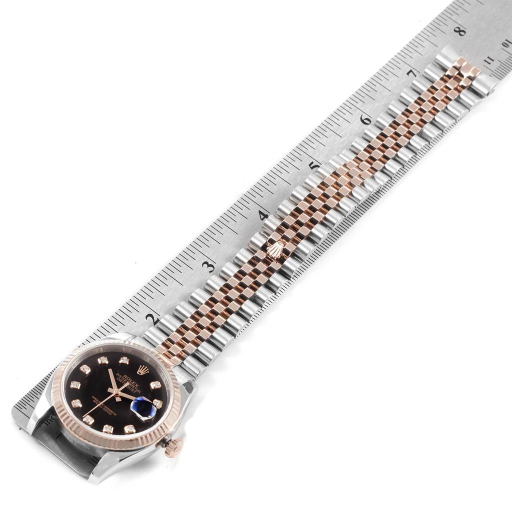 The image displays a Rolex Datejust 116231 Men's Steel and Gold (two tone) Black Dial 116231 Men's Steel and Gold (two tone) Black Dial watch laid flat next to a ruler, showcasing the dial, bezel, and bracelet.