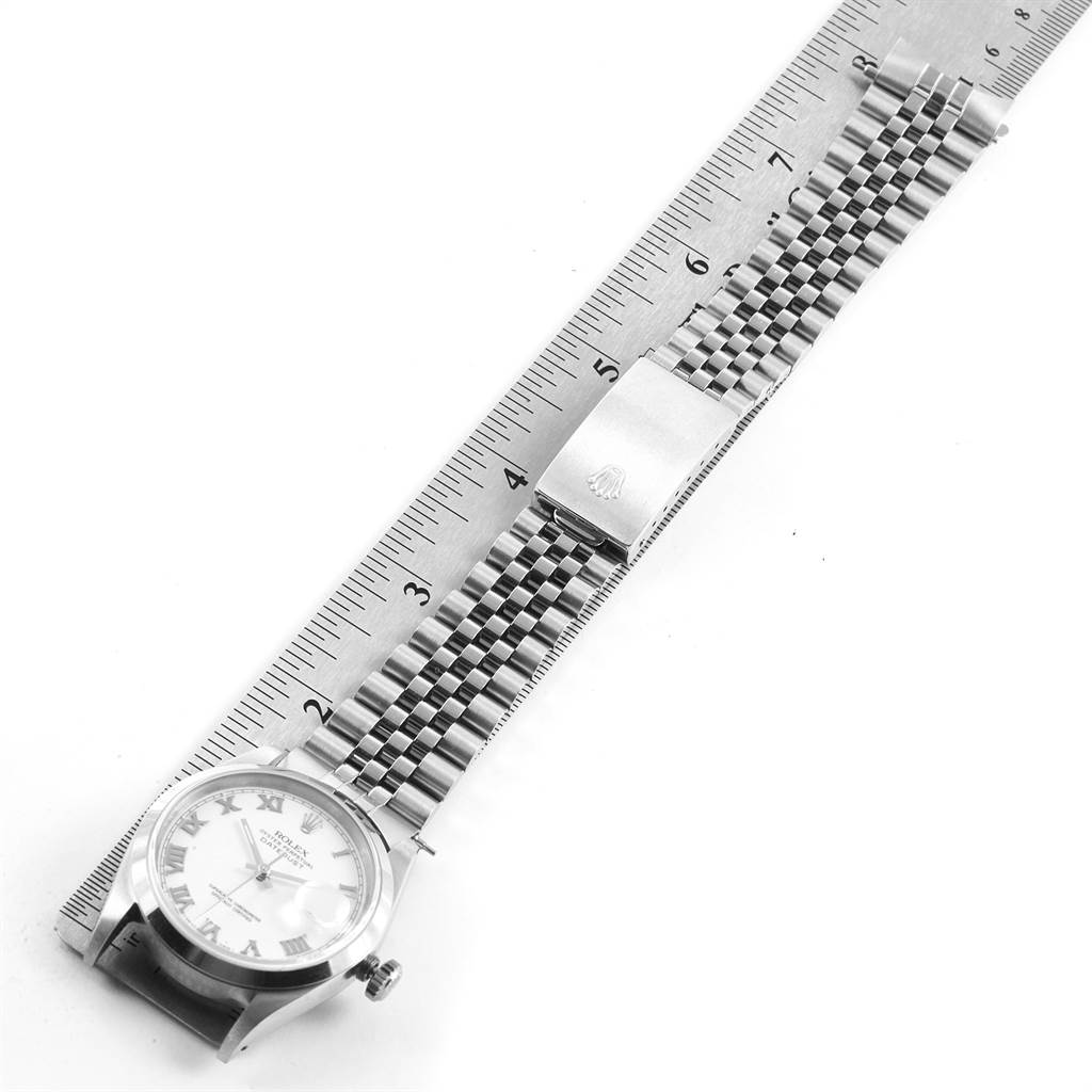 The Rolex Datejust 16200 Men's Stainless Steel White Dial 16200 Men's Stainless Steel White Dial watch is shown from an overhead angle, displaying the dial, bracelet, and clasp alongside a ruler.