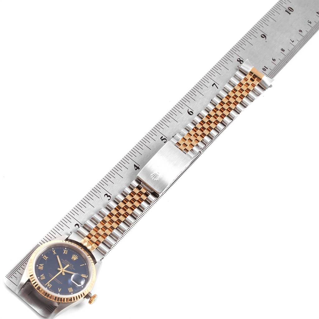 The watch shown is a Rolex Datejust 16233 Men's Steel and Gold (two tone) Blue Dial 16233 Men's Steel and Gold (two tone) Blue Dial model, displaying the face, crown, and band along a metal ruler.