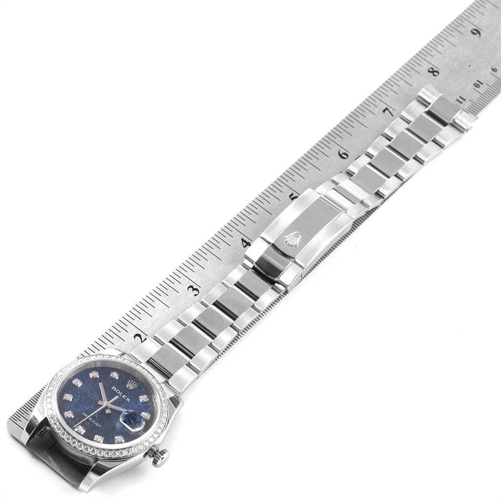 The Rolex Datejust 116244 Men's Stainless Steel Blue Dial 116244 Men's Stainless Steel Blue Dial watch is shown from a top-down angle, displaying the face, bracelet, and clasp alongside a ruler for scale.