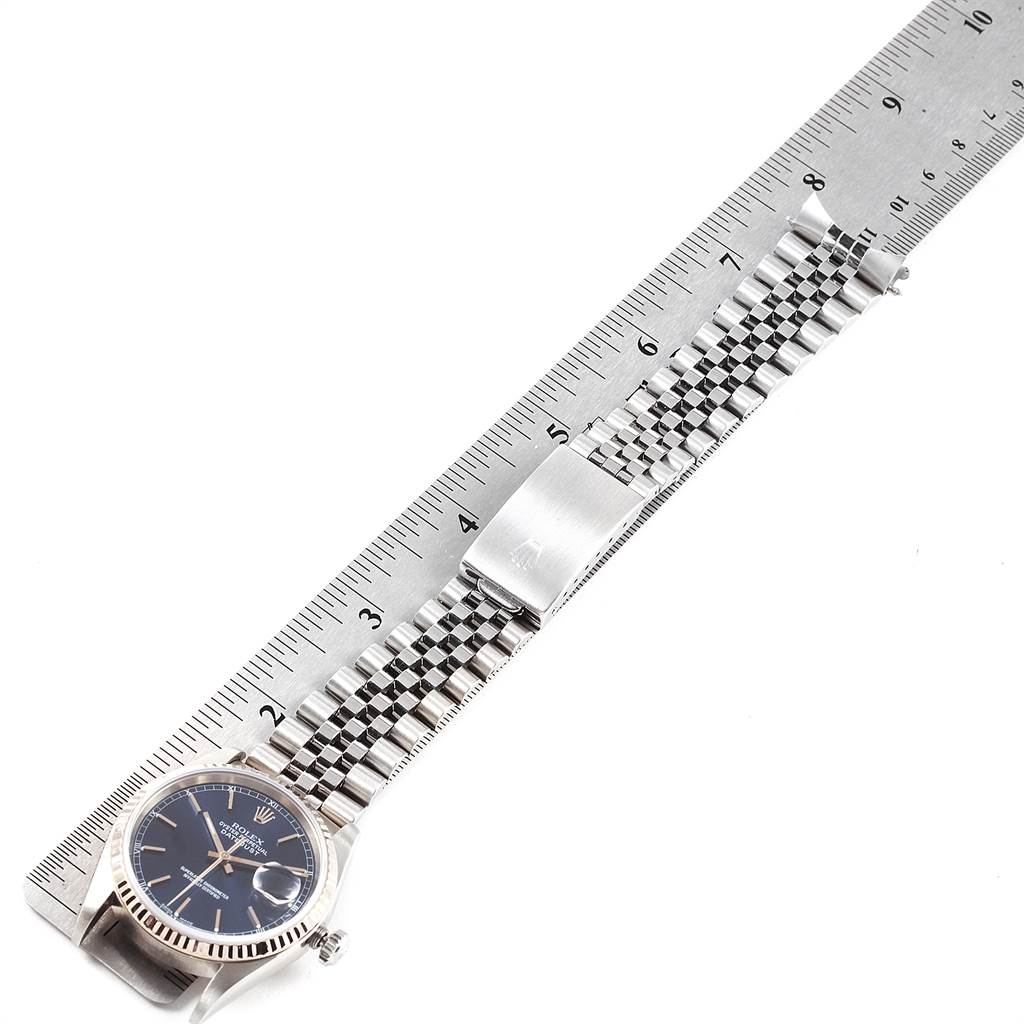 The Rolex Datejust 16234 Men
s Stainless Steel Blue Dial 16234 Men
s Stainless Steel Blue Dial watch is shown from an overhead angle with the dial and fully extended bracelet alongside a ruler.