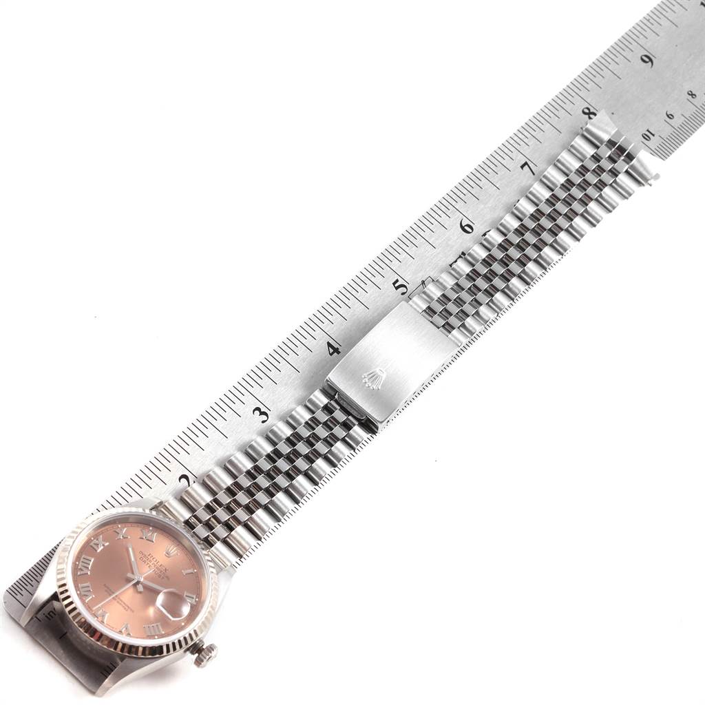 The image shows a Rolex Datejust 16234 Men
s Stainless Steel Pink Dial 16234 Men
s Stainless Steel Pink Dial watch laid flat beside a ruler, highlighting the face and a stainless steel jubilee bracelet.