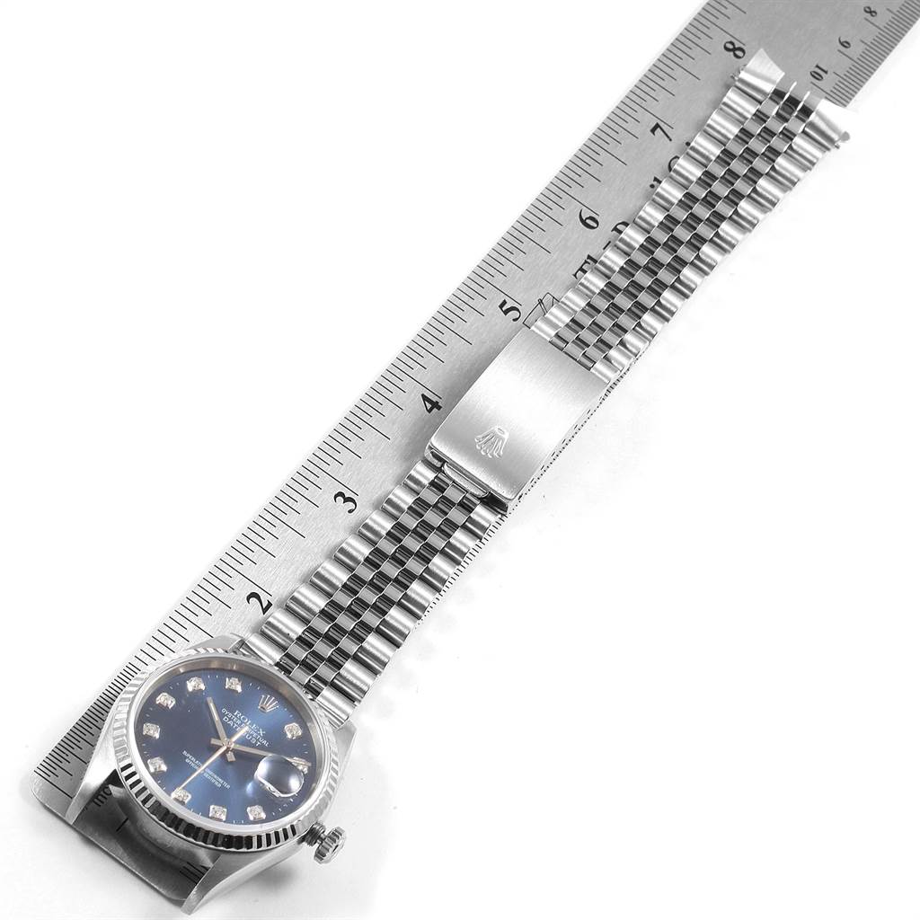 The image shows a Rolex Datejust 16234 Men's Stainless Steel Blue Dial 16234 Men's Stainless Steel Blue Dial watch laid flat next to a ruler, highlighting its face, bracelet, and clasp.