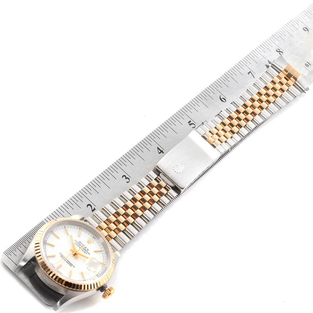 The image shows a Rolex Datejust 16233 Men's Steel and Gold (two tone) White Dial 16233 Men's Steel and Gold (two tone) White Dial watch lying flat alongside a ruler, displaying its face and two-tone metal bracelet.