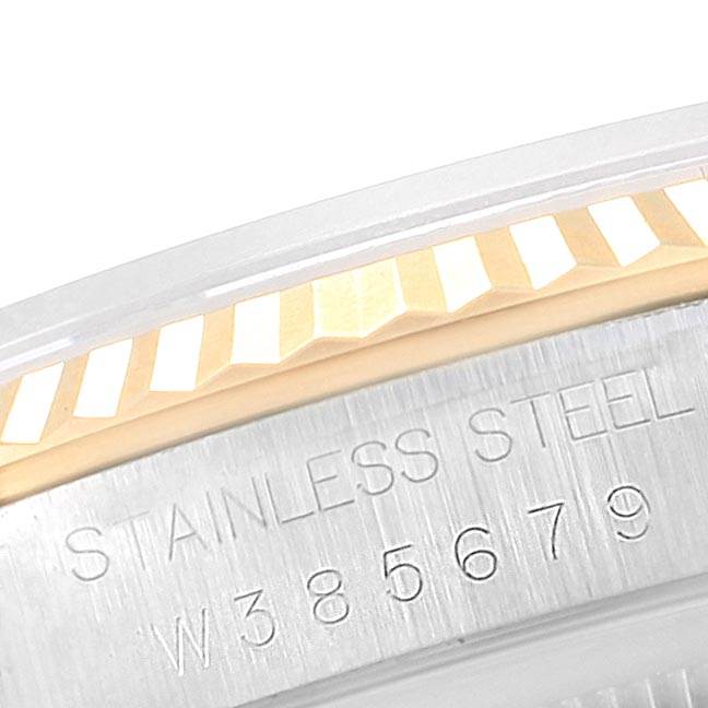 This image shows a close-up of the Rolex Datejust 16233 Men's Steel and Gold (two tone) White Dial 16233 Men's Steel and Gold (two tone) White Dial model's fluted bezel and part of the case back with engravings.